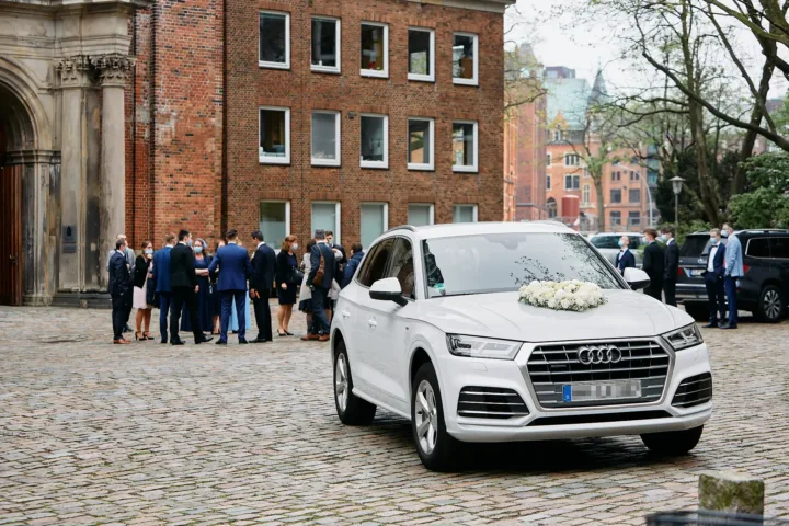 Gäste und Hochzeitsauto vor dem Trauort
