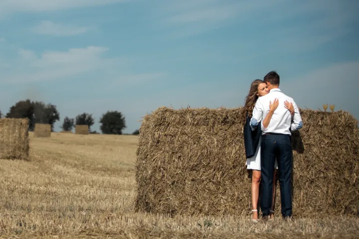 Sommerliches Paarshooting auf dem Feld mit Strohballen